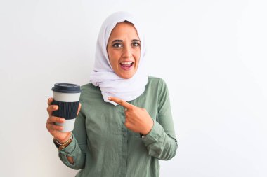 Geleneksel Müslüman başörtüsü takan genç, güzel bir Arap kadını kahve içerken mutlu bir şekilde elini ve parmağını gösterdi.