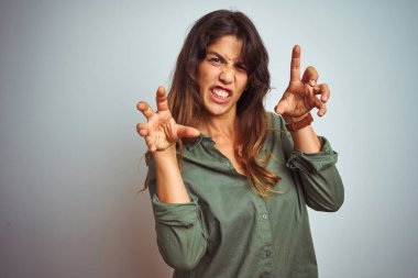 Yeşil tişörtlü genç bir kadın. Gri izole arka planda duruyor. Komik bir şekilde gülüyor.