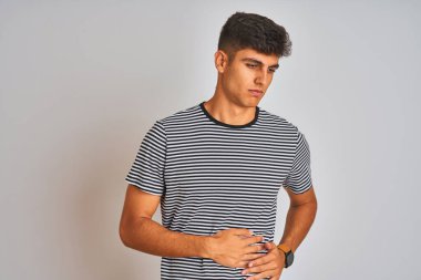 Deniz mavisi çizgili tişört giyen genç Hintli adam midesi bulanan, acı verici bir hastalıktan dolayı izole edilmiş beyaz arka planda duruyor. Ache kavramı.