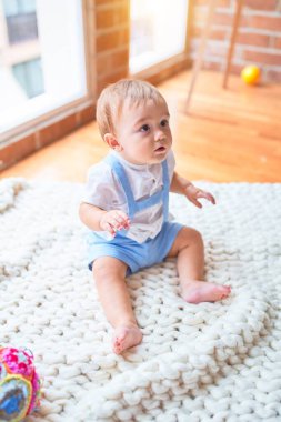 Anaokulunda battaniyenin üzerinde oturan güzel çocuk.