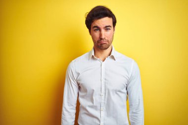Zarif gömlekli genç yakışıklı işadamı, izole edilmiş sarı arka planda duruyor. Depresyonda ve endişe içinde, kızgın ve korkmuş bir şekilde ağlıyor. Üzücü ifade.
