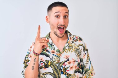 İzole edilmiş arka plan üzerinde Hawaii tişörtü giyen yakışıklı genç adam başarılı bir fikir işaret ediyor. Heyecanlı ve mutlu. Bir numara..
