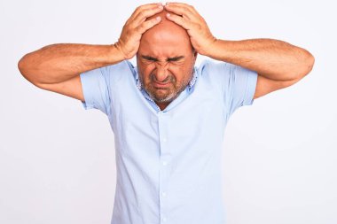 Orta yaşlı yakışıklı bir adam, izole edilmiş beyaz arka plan üzerinde dikilip acı ve migren yüzünden çaresiz ve stresli bir şekilde acı çekiyor. Ellerini başının üstüne koy..