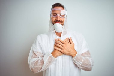 Profesyonel işçi teçhizatı takan ressam izole edilmiş arka plan üzerinde elleri göğsünde, gözleri kapalı ve yüzünde minnet dolu bir jest ile gülümsüyor. Sağlık kavramı.