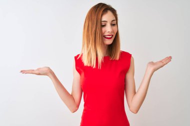 Kırmızılı iş kadını zarif kırmızı elbiseler giyiyor. İzole edilmiş beyaz arka planda duruyor. Gülümsüyor.