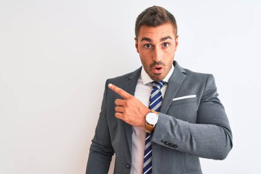 Takım elbiseli ve kravatlı genç yakışıklı bir iş adamı. Şaşırmış bir şekilde parmağını yana uzatmış, ağzı açık bir şekilde hayrete düşmüş..