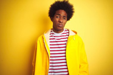 Siyah saçlı Afro-Amerikalı bir adam izole edilmiş sarı arka planda dikiliyor. Depresyonda ve endişe içinde, kızgın ve korkmuş bir halde. Üzücü ifade.