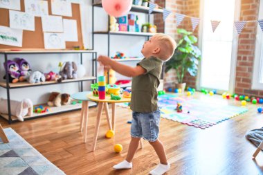 Anaokulunda oyuncaklarla oynayan beyaz bir çocuk. Anaokulu