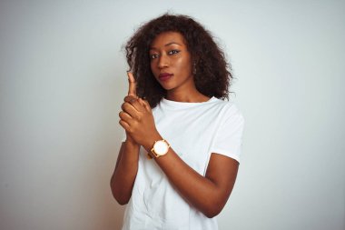 Siyah tişörtlü genç Afro-Amerikalı kadın izole edilmiş beyaz arka plan üzerinde duruyor. Sembolik bir silah tutuyor, el hareketleriyle cinayet silahlarıyla oynuyor, kızgın surat ifadeleri takınıyor.