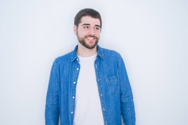 Beyaz yalıtılmış arka planda kot ceket giyen yakışıklı İspanyol bir adam yüzünde gülümseme, doğal bir ifade ile yan yana bakıyor. Kendinden emin gülen.