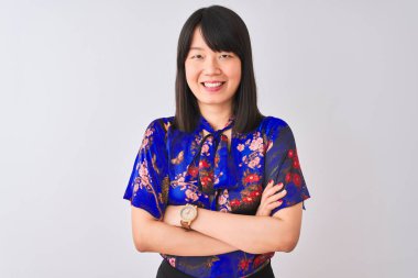 Yazlık çiçekli tişört giyen genç, güzel Çinli bir kadın izole edilmiş beyaz arka plan üzerinde kollarını kavuşturup kameraya bakarken gülümseyen mutlu bir yüz. Pozitif kişi.