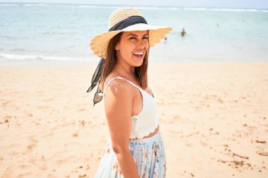 Genç ve güzel bir kadın gülümseyerek kumsalda yaz tatilinin tadını çıkarıyor.