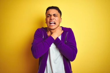 Mor kazak giyen genç Brezilyalı adam izole edilmiş sarı arka planda dikilip boğularak ölme diye bağırıyor. Sağlık problemi. Boğulma ve intihar konsepti.