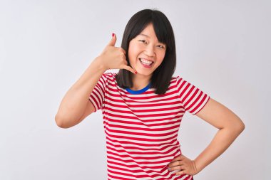 İzole edilmiş beyaz arka plan üzerinde kırmızı çizgili tişört giyen genç ve güzel Çinli kadın telefonla el ve parmaklarıyla telefonla konuşuyor gibi gülümsüyor. İletişim kavramları.