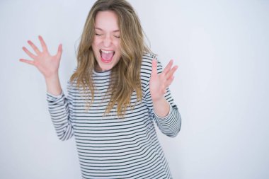 Güzel sarışın, mavi gözlü, çizgili süveter giyen, beyaz, izole edilmiş arka plan deliliğini kutlayan ve başarı için hayrete düşen, kollarını kaldırmış, gözleri açık, heyecanlı bir şekilde çığlık atan bir kız. Kazanan konsept