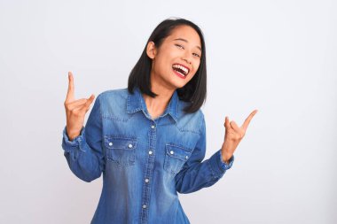 Kotlu tişört giyen genç ve güzel bir Çinli kadın izole edilmiş beyaz arka planda duruyor çılgın bir ifadeyle elleri havada rock sembolü yapıyor diye bağırıyor. Müzik yıldızı. Ağır konsept.