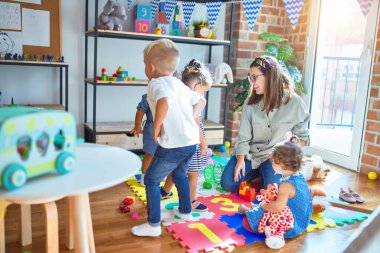 Güzel öğretmen ve bir grup çocuk anaokulunda bir sürü oyuncakla oynuyorlar.