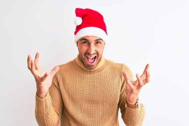 Yılbaşı ve balıkçı yaka kazak giyen genç yakışıklı bir adam izole arka planda çılgın ve başarıyı kutluyor kollarını kaldırmış ve gözlerini kapatmış heyecanlı çığlıklar atıyor. Kazanan konsept