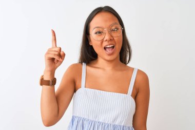 İzole edilmiş beyaz arka plan üzerine çizgili elbise ve gözlük takan genç Çinli kadın başarılı bir fikirle parmağı işaret ediyor. Heyecanlı ve mutlu. Bir numara..