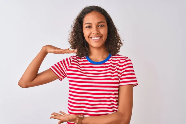 赤の縞模様のTシャツを着た若いブラジル人女性は 大小のサインを示す手で孤立した白い背景ジェスチャーの上に立って シンボルを測定します カメラを見て微笑んだ 概念の測定 — ストック写真