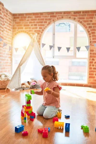 Schöne Blonde Kleinkind Mädchen Spielt Mit Plastikklötzen Einen Turm Kindergarten — Stockfoto