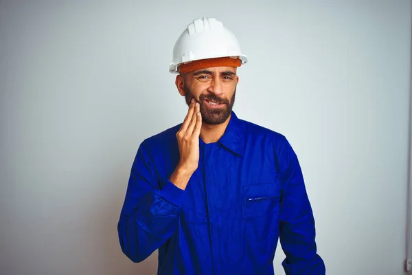 歯痛や歯の病気のために痛みを伴う表現で手で手に触れる孤立した白い背景の上に制服やヘルメットを身に着けているハンサムなインドの労働者の男性 歯医者の概念 — ストック写真