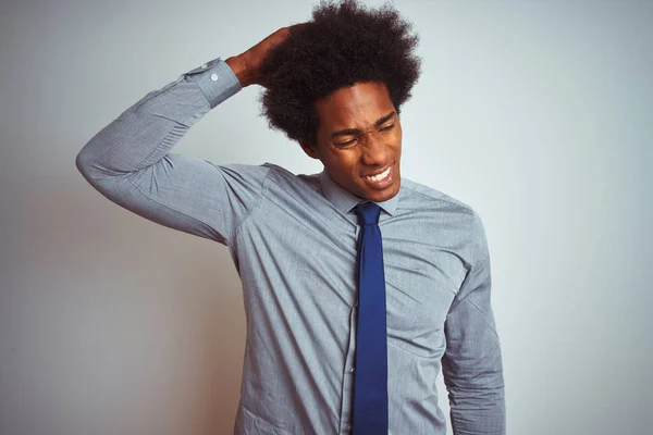 American business man with afro hair wearing shirt and tie over isolated white background confuse and wonder about question. Uncertain with doubt, thinking with hand on head. Pensive concept.