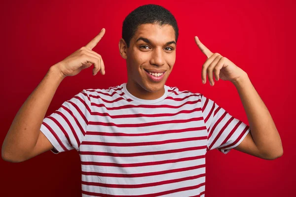 Mladý Pohledný Arabský Muž Pruhovaném Tričku Izolovaném Červeném Pozadí Úsměvem — Stock fotografie