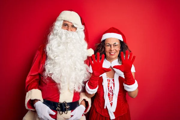 Paar Mittleren Alters Weihnachtsmannkostüm Und Brille Vor Isoliertem Rotem Hintergrund — Stockfoto