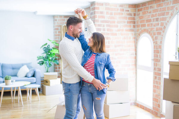 Young beautiful couple dancing  at new home around cardboard boxes