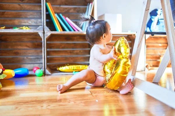 Beautiful infant happy at kindergarten around colorful toys