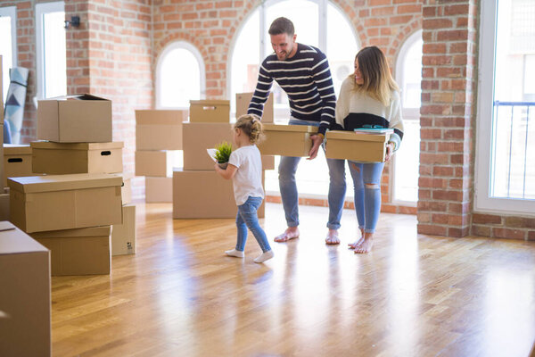 Beautiful family, parents and little girl at new home around cardboard boxes