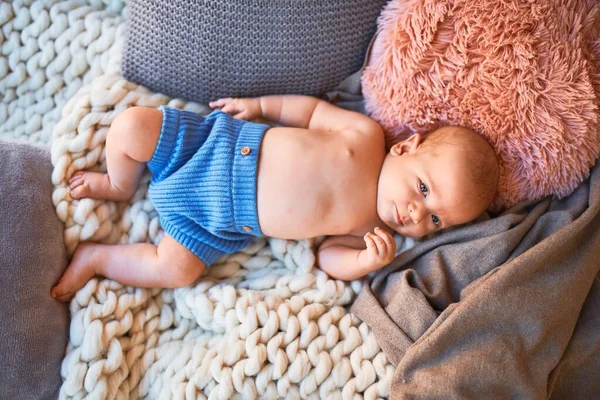 Adorable baby lying down on the sofa over blanket at home. Newborn relaxing and resting comfortable