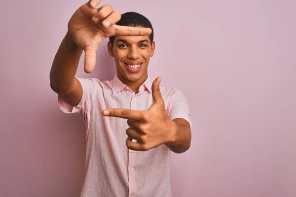 孤立したピンクの背景の上に立つカジュアルなシャツを着た若いハンサムなアラブ人男性は 幸せな顔をした手と指でフレームを作り笑顔 創造性と写真の概念 — ストック写真