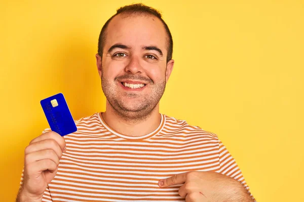 Νεαρός Άνδρας Μπλε Πιστωτική Κάρτα Στέκεται Πάνω Από Απομονωμένο Κίτρινο — Φωτογραφία Αρχείου