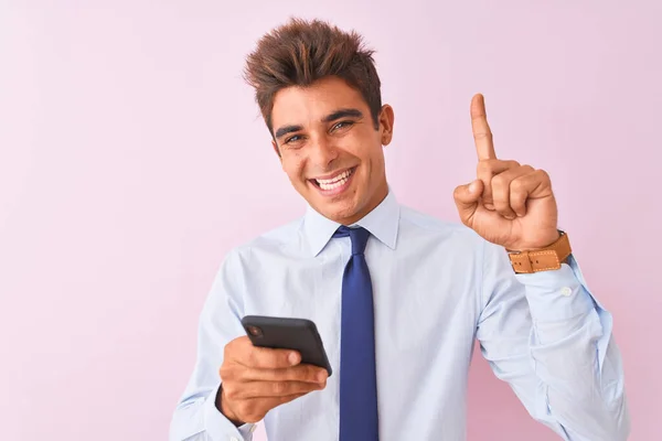 年轻英俊的生意人用智能手机站在孤立的粉色背景上 惊讶地发现一个想法或问题 满脸喜形于色 指手画脚 位居第一 — 图库照片