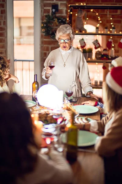 Mutlu ve kendinden emin gülümseyen güzel bir kadın grubu. Her birinin elinde şarap bardağıyla evde Noel 'i kutlayan konuşmaları var.