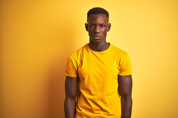Young african american man wearing casual t-shirt standing over isolated yellow background skeptic and nervous, frowning upset because of problem. Negative person.