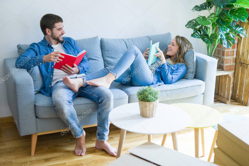 Young couple relaxing on the sofa reading a book, taking a break