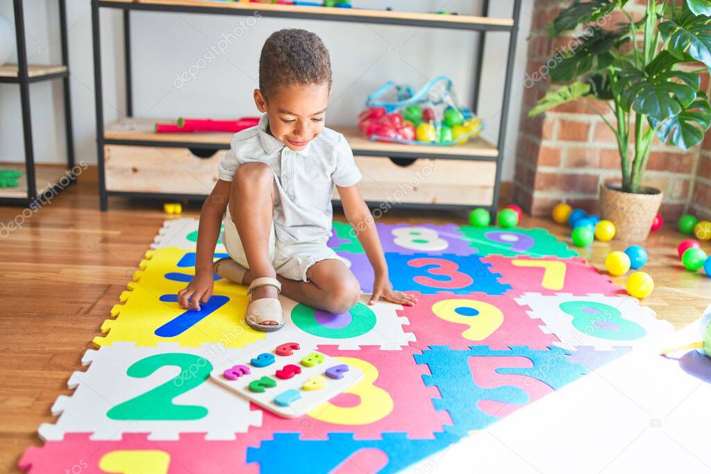 Beautiful african american toddler playing with maths game using numbers at kindergarten