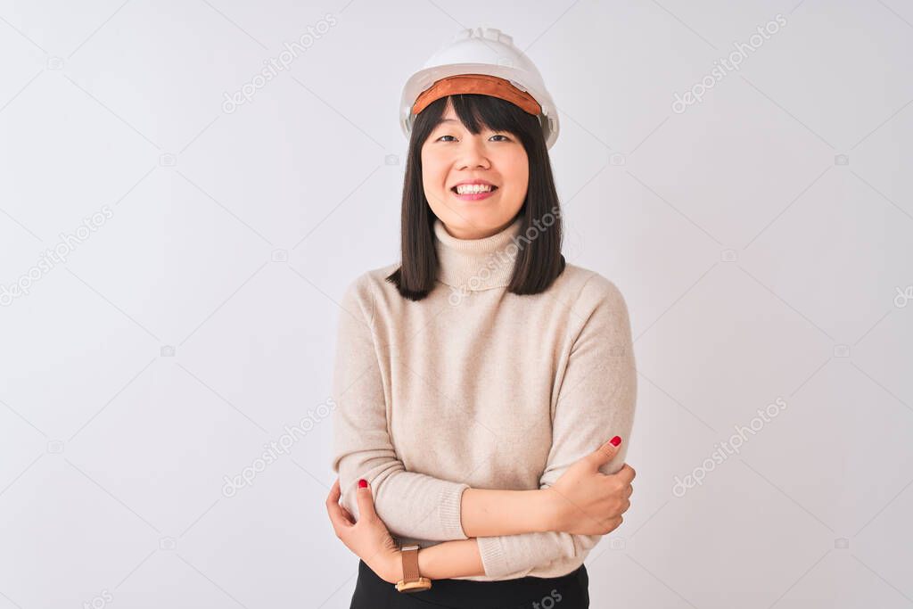 Young beautiful Chinese architect woman wearing helmet over isolated white background happy face smiling with crossed arms looking at the camera. Positive person.