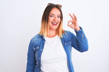 İzole edilmiş beyaz arka plan üzerinde kot gömlek giyen güzel bir kadın gülümsüyor ve el ve parmaklarıyla 