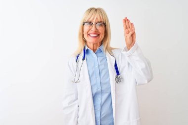 Gözlüklü ve steteskop takan orta yaşlı doktor kadın, izole edilmiş beyaz arka planı gösteriyor ve parmaklarını dört numarayı gösterirken kendinden emin ve mutlu gülümsüyor..
