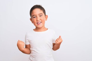 Güzel çocuk, izole edilmiş beyaz arka planda dikilen sıradan bir tişört giyiyor çok mutlu ve heyecanlı bir şekilde kollarını kaldırıp, gülümseyerek ve başarı için çığlık atarak kazanan bir jest yapıyor. Kutlama konsepti.