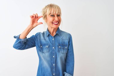 İzole edilmiş beyaz arka plan üzerinde duran sıradan bir kot giyen orta yaşlı kadın gülümsüyor ve el hareketleriyle küçük beden işareti yaparak kameraya bakıyor. Ölçü kavramı.