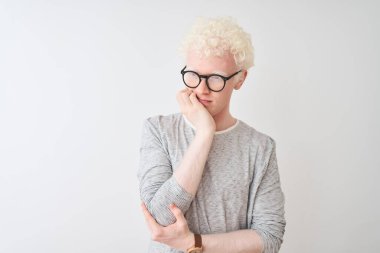 Genç, sarışın, çizgili tişört ve gözlük takan izole edilmiş beyaz arka planda yorgun ve bunalımlı görünmekten sıkılmış kolları çaprazlanmış genç bir adam..