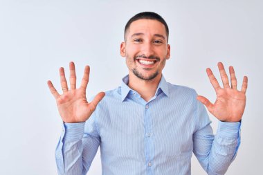 Genç yakışıklı iş adamı izole edilmiş arka planda duruyor ve 10 numarayı gösterip işaret ederken kendinden emin ve mutlu bir şekilde gülümsüyor..