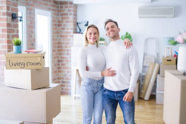 Genç ve güzel bir çift, yeni evlerinde karton kutuların etrafında mutlu ve havalı bir gülümsemeyle dikiliyorlar. Şanslı kişi..