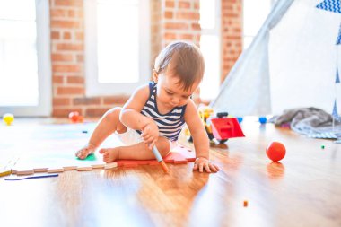 Anaokulunda bir sürü oyuncakla oynayan sevimli bir çocuk.