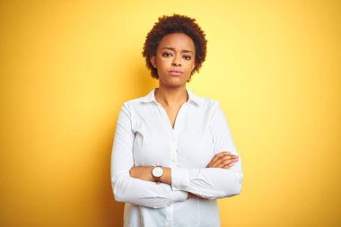 Afrika kökenli Amerikalı iş kadını izole edilmiş sarı arka plan şüphecisi ve gergin kollarını kavuşturmuş yüz ifadesini onaylamıyor. Negatif kişi.